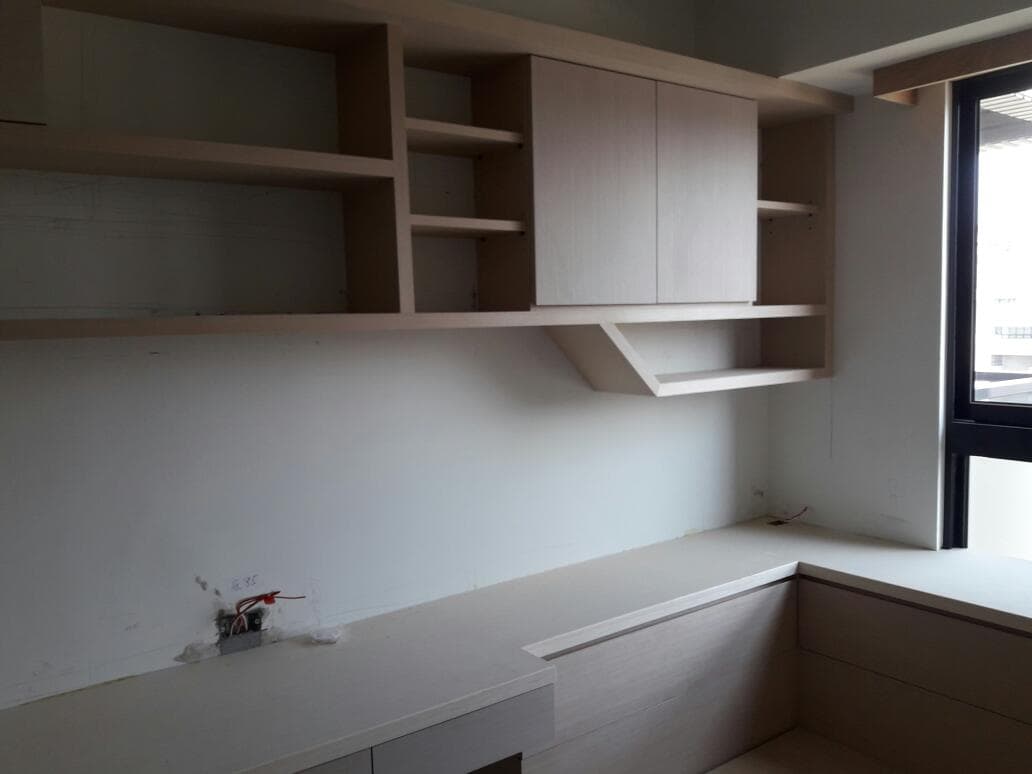 這張照片是一間書房,房間裡最顯眼的部分是房間右側的窗戶,窗戶的下方是白色的書桌,桌面看起來很乾淨。