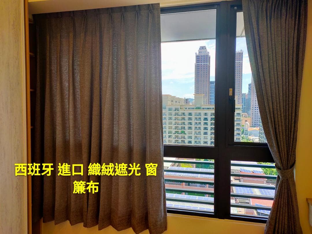 1) 照片顯示一個房間裡有一扇窗戶和窗簾,窗戶外面是高樓建築,窗簾是深棕色的