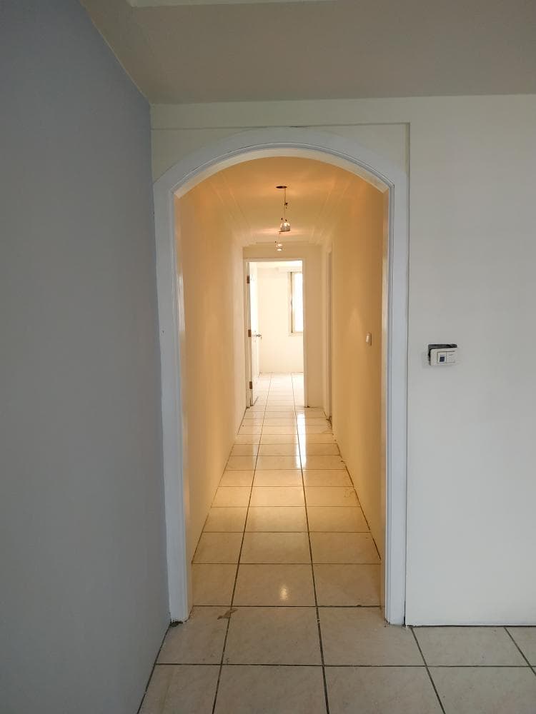 這張照片是走廊和客廳之間的拱形通道,通道以白色為底,鋪著淺色的瓷磚。