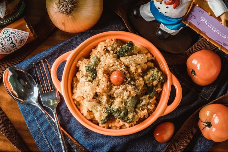 這張「義大利燉飯」的照片是一碗橙色的燉飯,裡面有雞肉、花椰菜、番茄和起司。