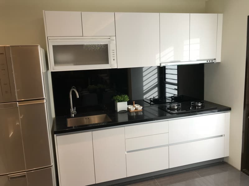 這張照片是現代化的廚房,最重要的部分是黑色的大理石台面,上面有洗碗槽、水龍頭、爐子,以及幾個小容器。