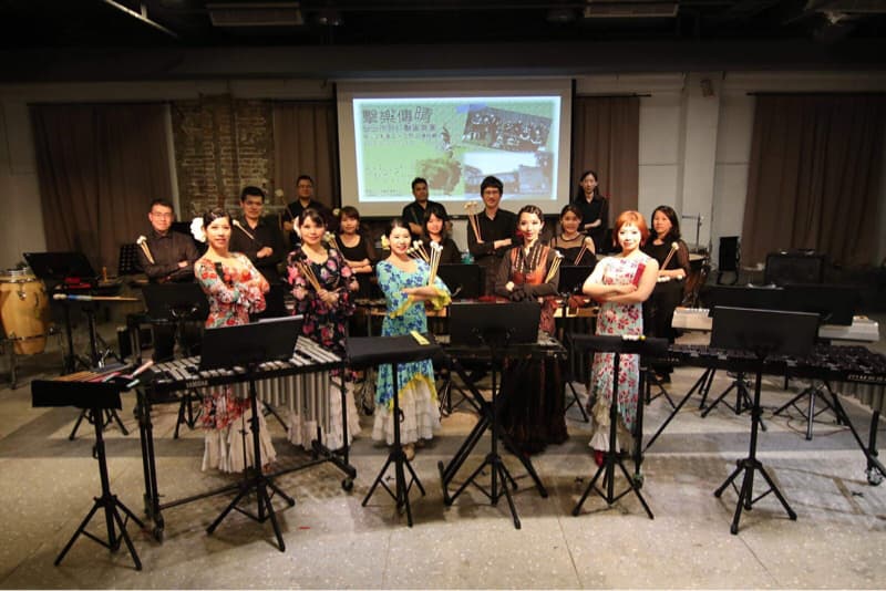 這張「樂團合照」的照片是一群音樂家,他們在舞臺上,手持樂器,正在準備演出。照片中有許多人,他們穿著制服,看起來很專業。舞臺上擺放了許多樂器,包括鼓、鍵盤和絃樂器。他們似乎正在準備一個重要的演出,看起來很興奮。