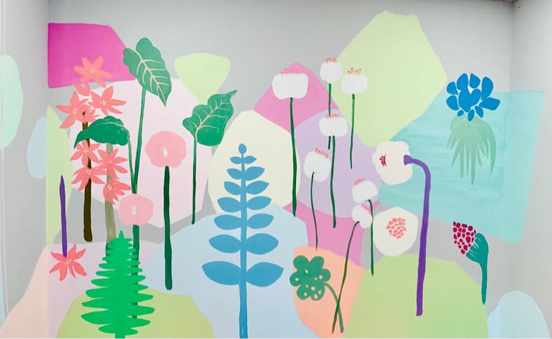 這張「牆上繪畫」的照片是各種花卉和植物,例如紅色的花、白色的花、綠色的葉子、藍色的花和粉紅色的花。