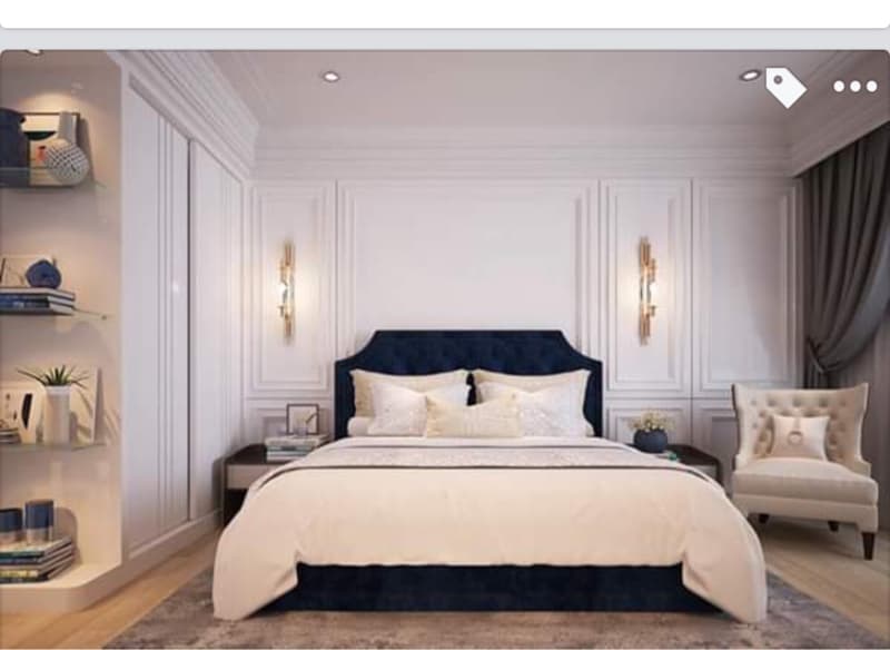 這張「臥室」的照片是一間裝潢精緻的房間,裡面有一張大床,床頭板是深藍色的,床單是白色的,床邊有兩個金色的壁燈,牆上也有一些白色的裝飾線條,房間的角落還有一個白色的單人沙發,整體看起來非常舒適和優雅。