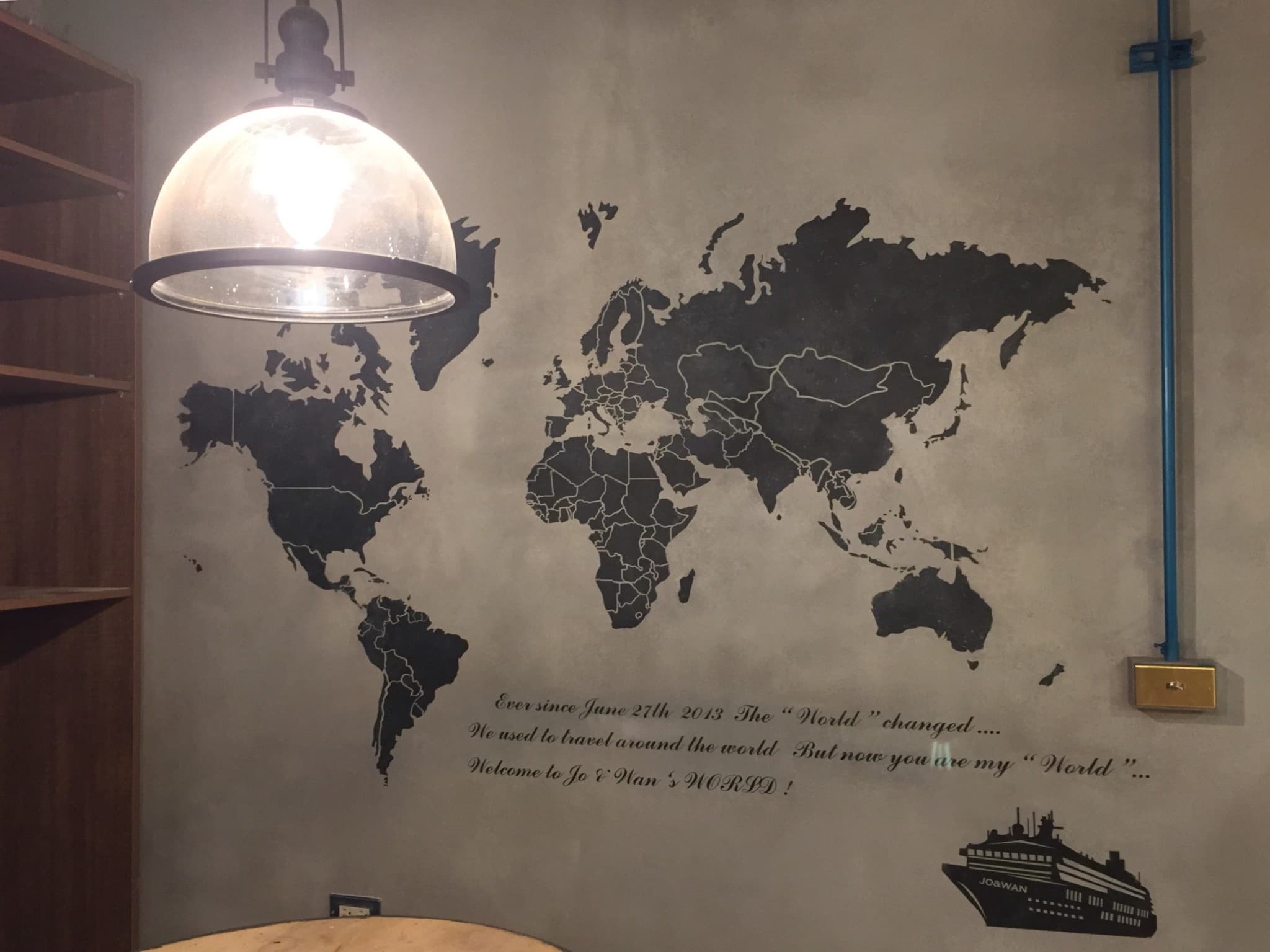 這張「牆壁」的照片是一個簡約的室內設計,上面畫著黑色的世界地圖,還有一盞燈和一些文字。