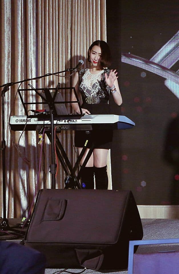 這張「一位年輕女子在鍵盤上演奏」的照片是,她穿著黑色的蕾絲連衣裙,站在鍵盤前演奏。