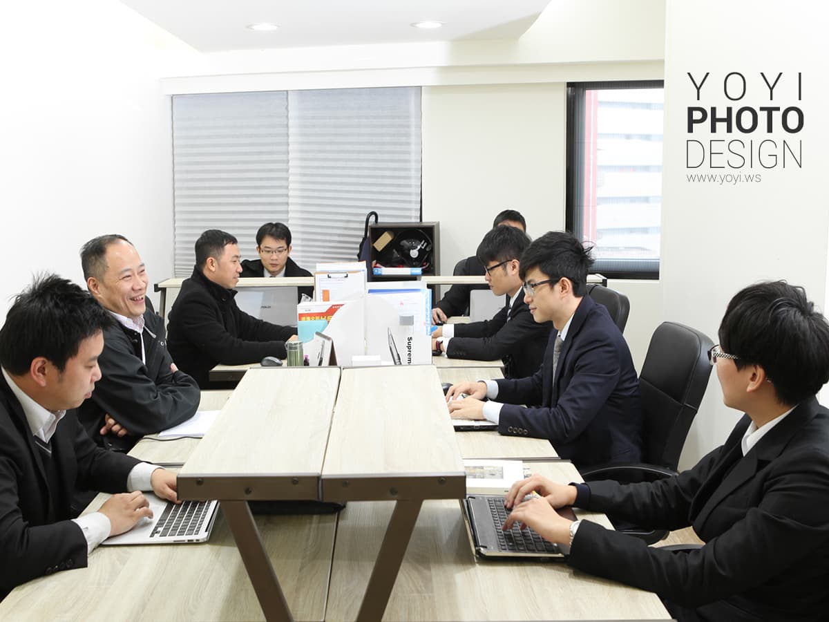 這張「會議室」的照片是幾位男士在開會,他們圍著一張桌子,桌子上放著筆記本電腦和文件。