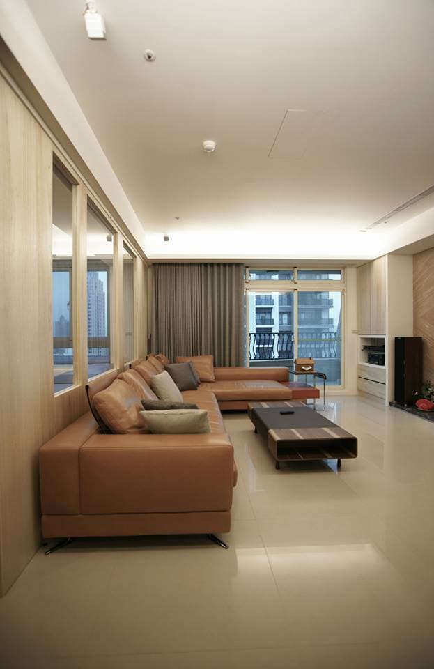 這張客廳的照片是一個現代化的沙發,沙發是L形的,皮革材質,顏色是棕色。 沙發前面有一個木質的茶几。 背景是落地窗,可以看到外面的風景。