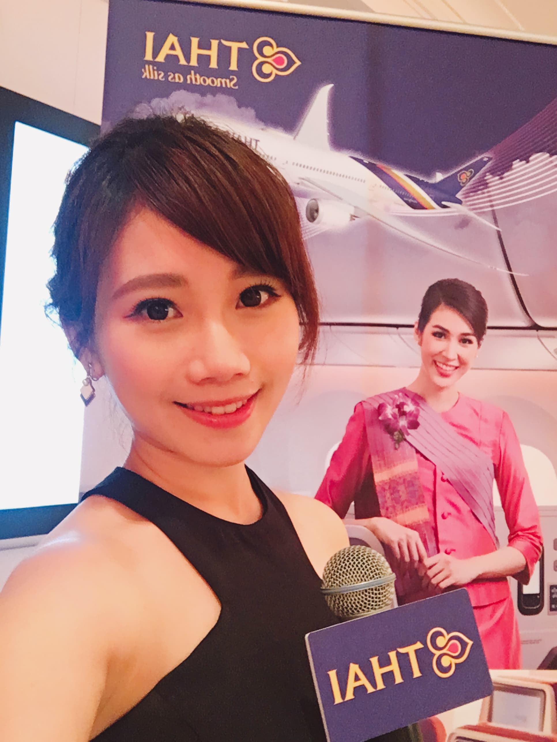 這張「女子站在飛機前,手拿麥克風,並和另一名穿著空服員制服的女子合照」的照片是。