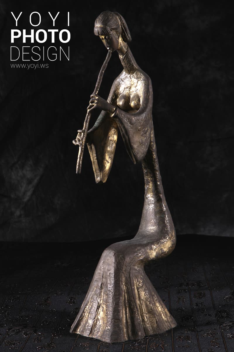 這張「雕塑」的照片是一個穿著長袍的女性,她正在演奏一種樂器。