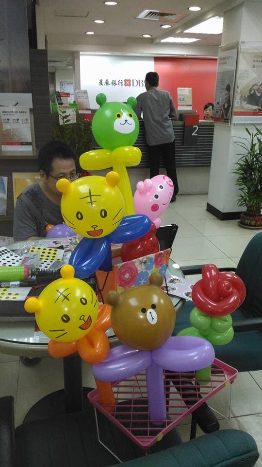 1) 照片顯示在銀行櫃台前有許多氣球動物,有兩位成人和一個小孩