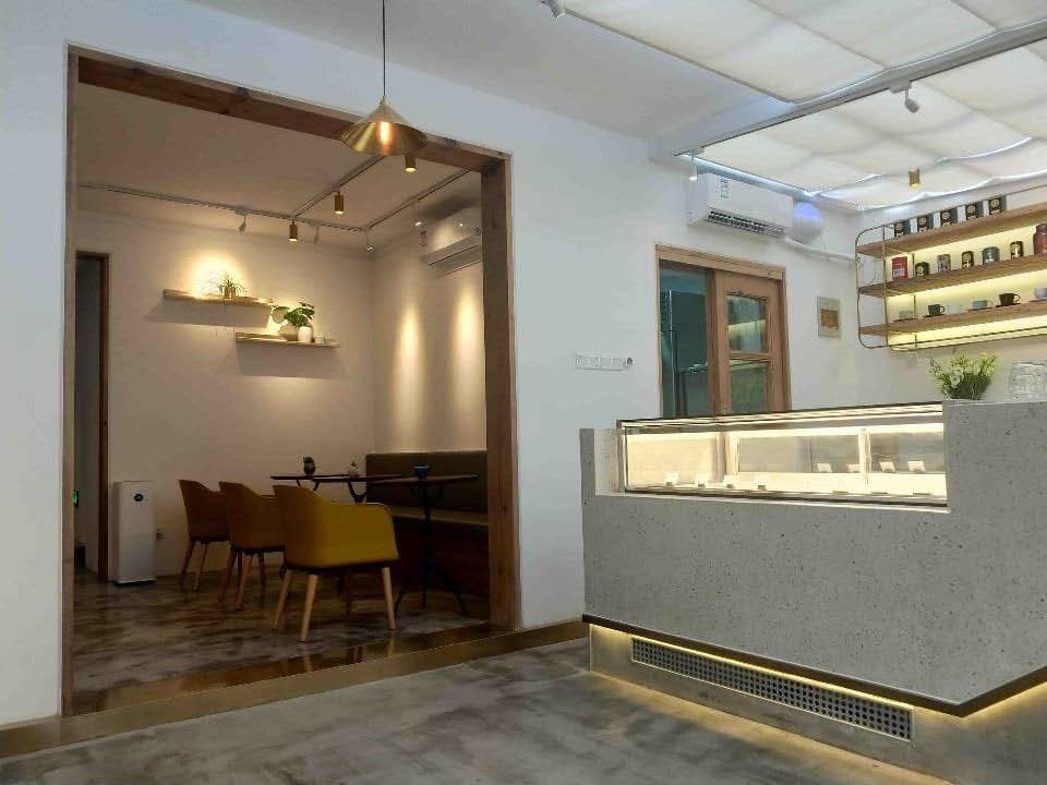 這張照片是一家現代風格的咖啡廳,最重要的是展示櫃,它以淺色石材製成,櫃臺上方的玻璃展示櫃裡陳列著琳瑯滿目的甜點。