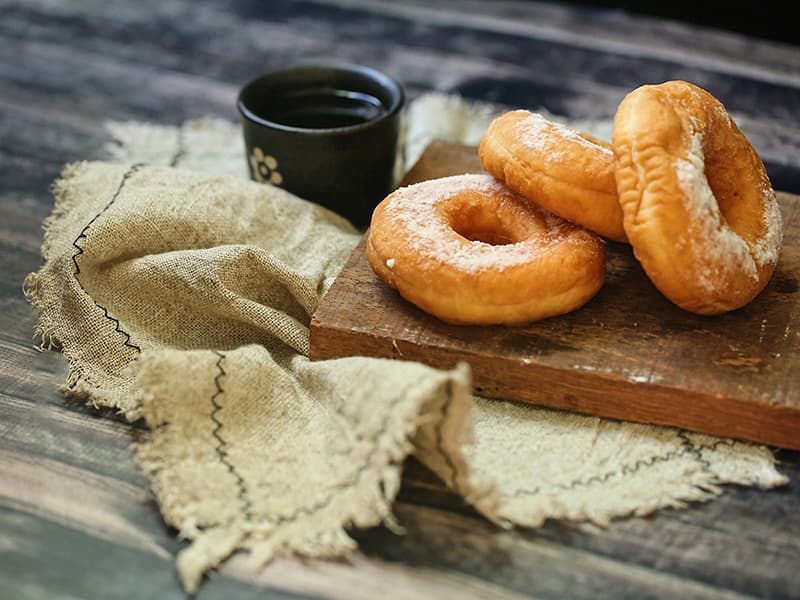 這張照片是三塊甜甜圈在木板上,最下面那塊甜甜圈最大,看起來最美味。