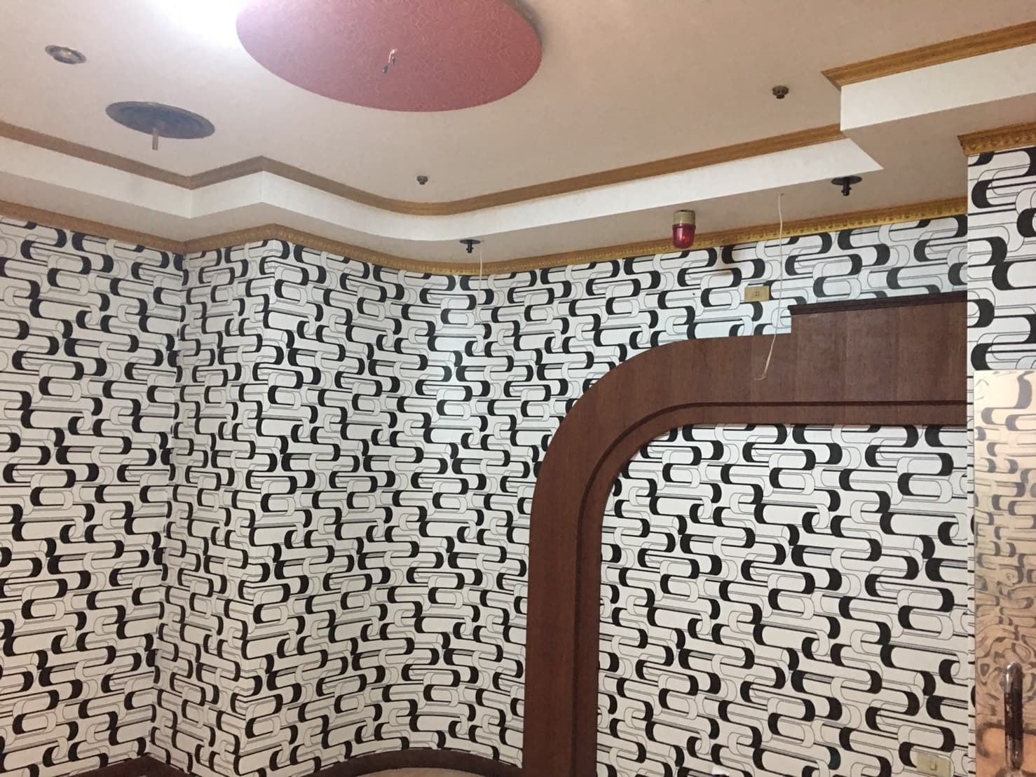 1) 照片顯示一個帶有幾何圖案壁紙的房間牆壁