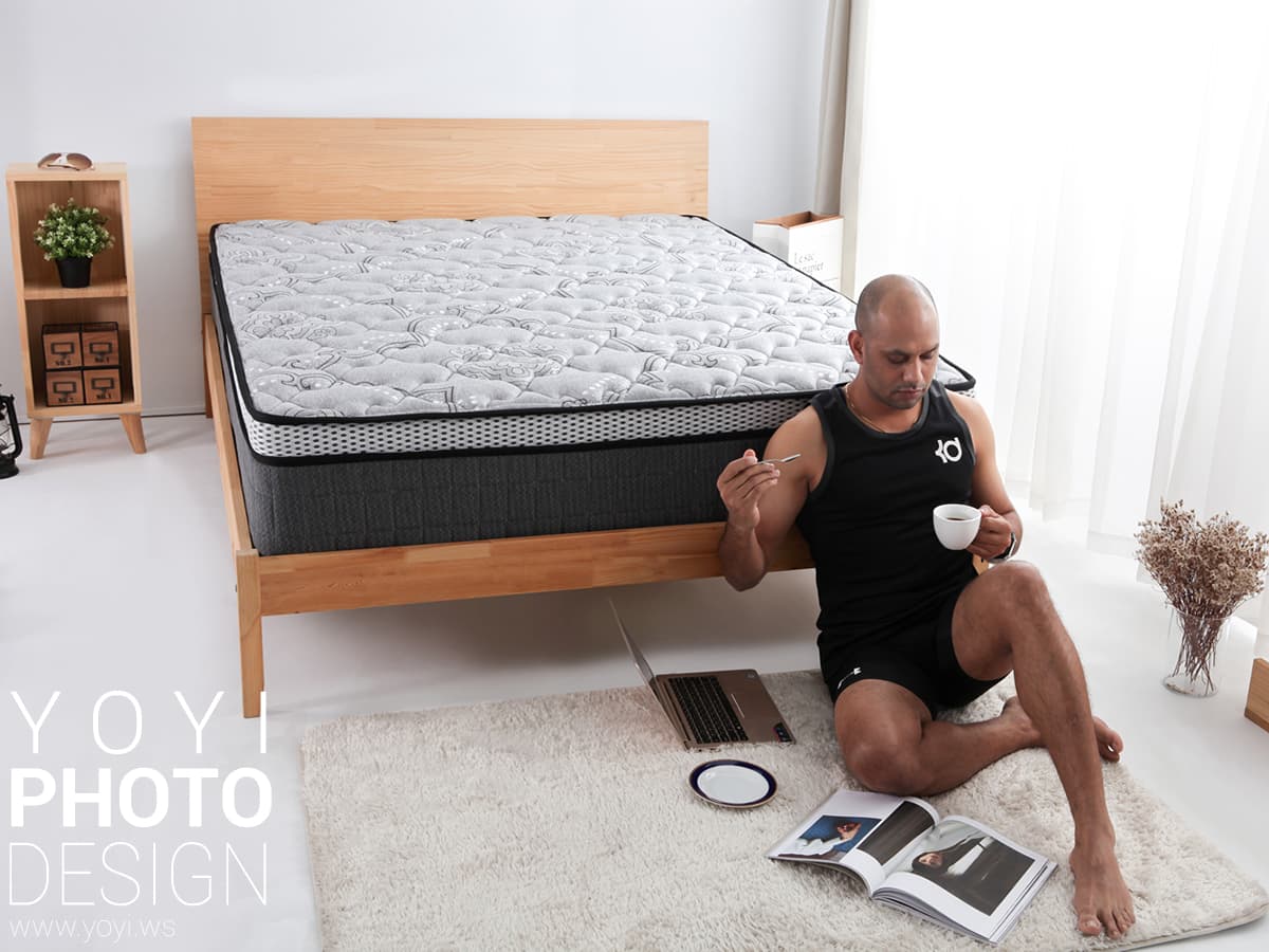 這張照片是一張床和一個喝著咖啡的男人。