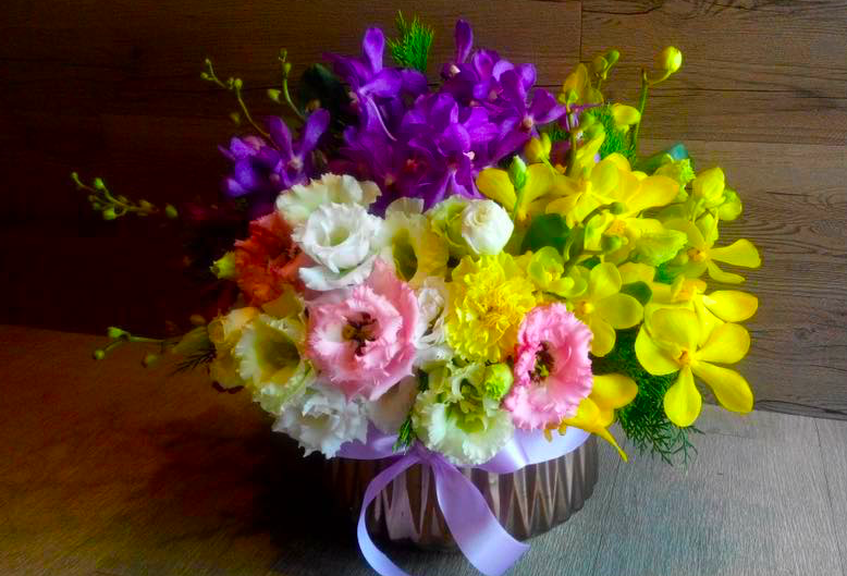 1) 照片中是一束鮮豔的花,以木質花盒盛裝,花束中包含了黃色、紫色、粉紅色和白色等不同色系的花朵