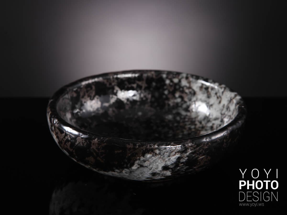 這張「碗」的照片是一個黑色的陶瓷碗,表面佈滿了白色的斑點。