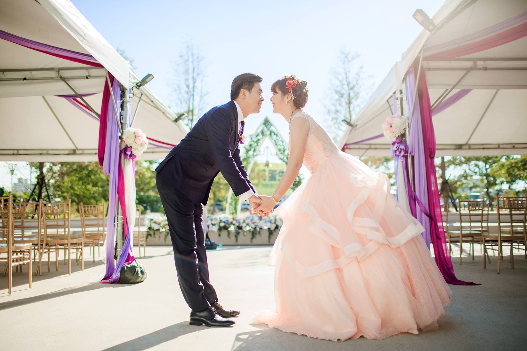 這張照片是一對新人正在結婚典禮上交換誓言。他們彼此深情對望,手牽著手,臉上充滿幸福的笑容。他們身穿婚紗和禮服,在充滿浪漫氣氛的佈置下,準備迎接人生新的旅程。