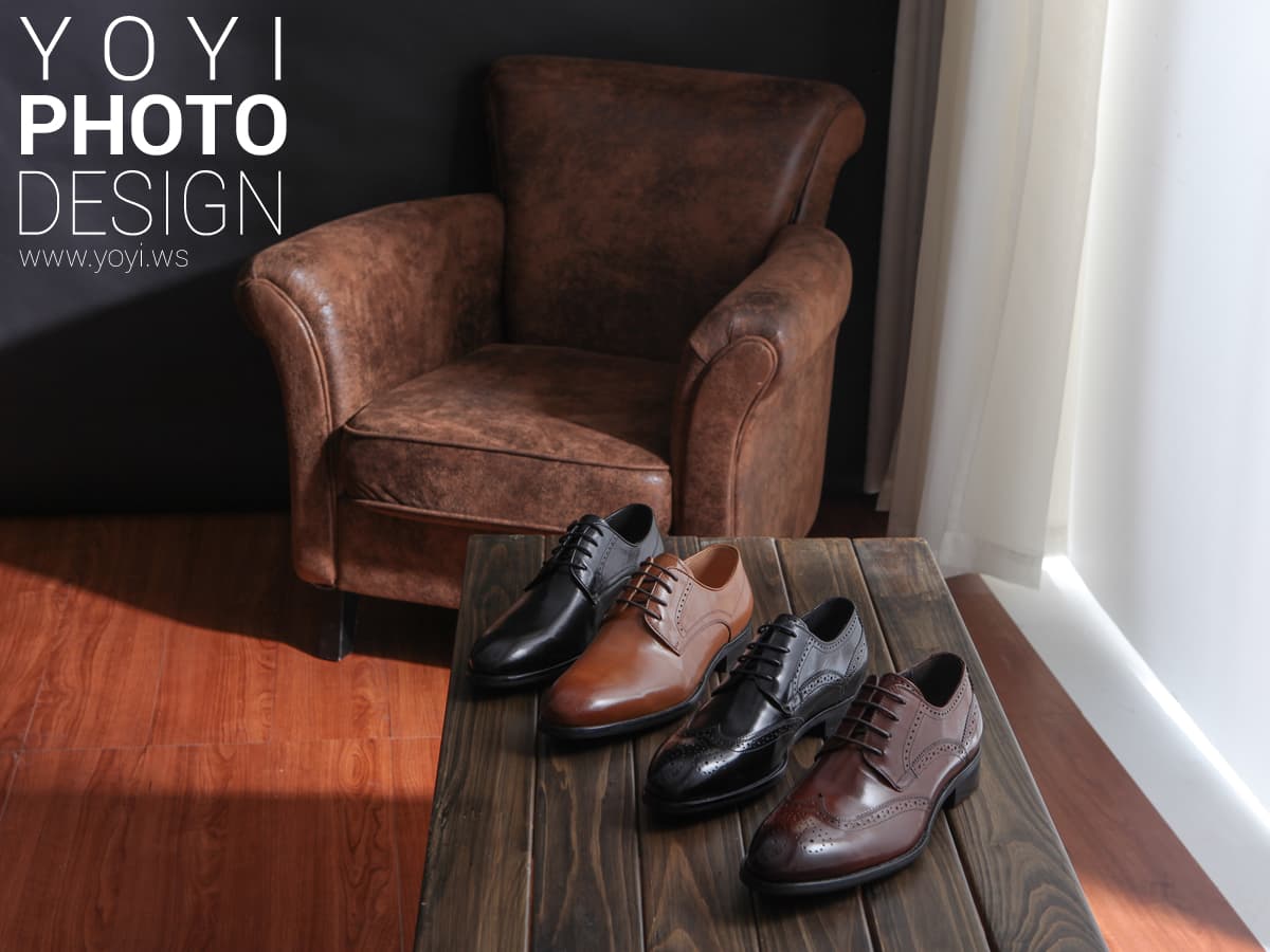 這張「皮鞋」的照片是四雙不同款式和顏色的皮鞋,擺放在一張木質桌面上,旁邊有一張褐色的皮沙發。