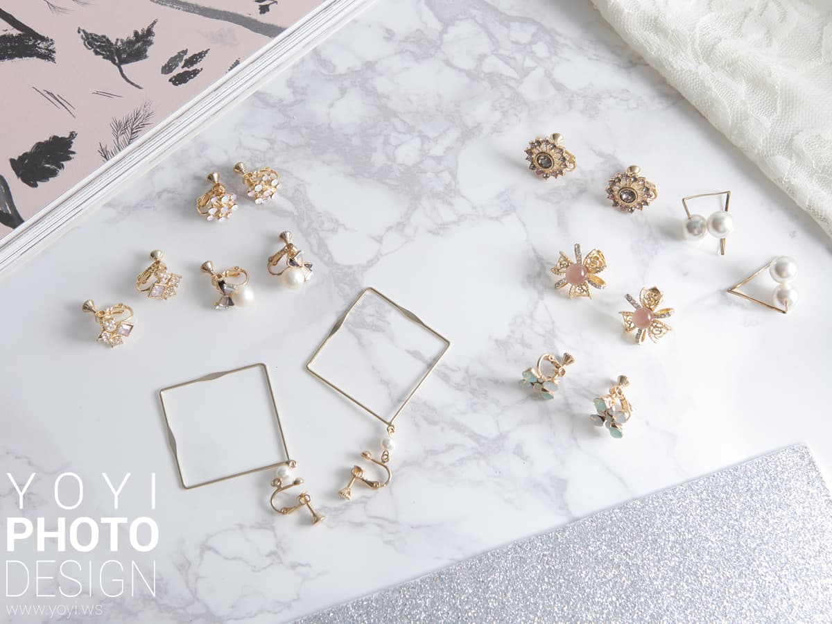 這張「耳環」的照片是一些用金屬和珍珠做成的耳環,放在白色大理石背景上。