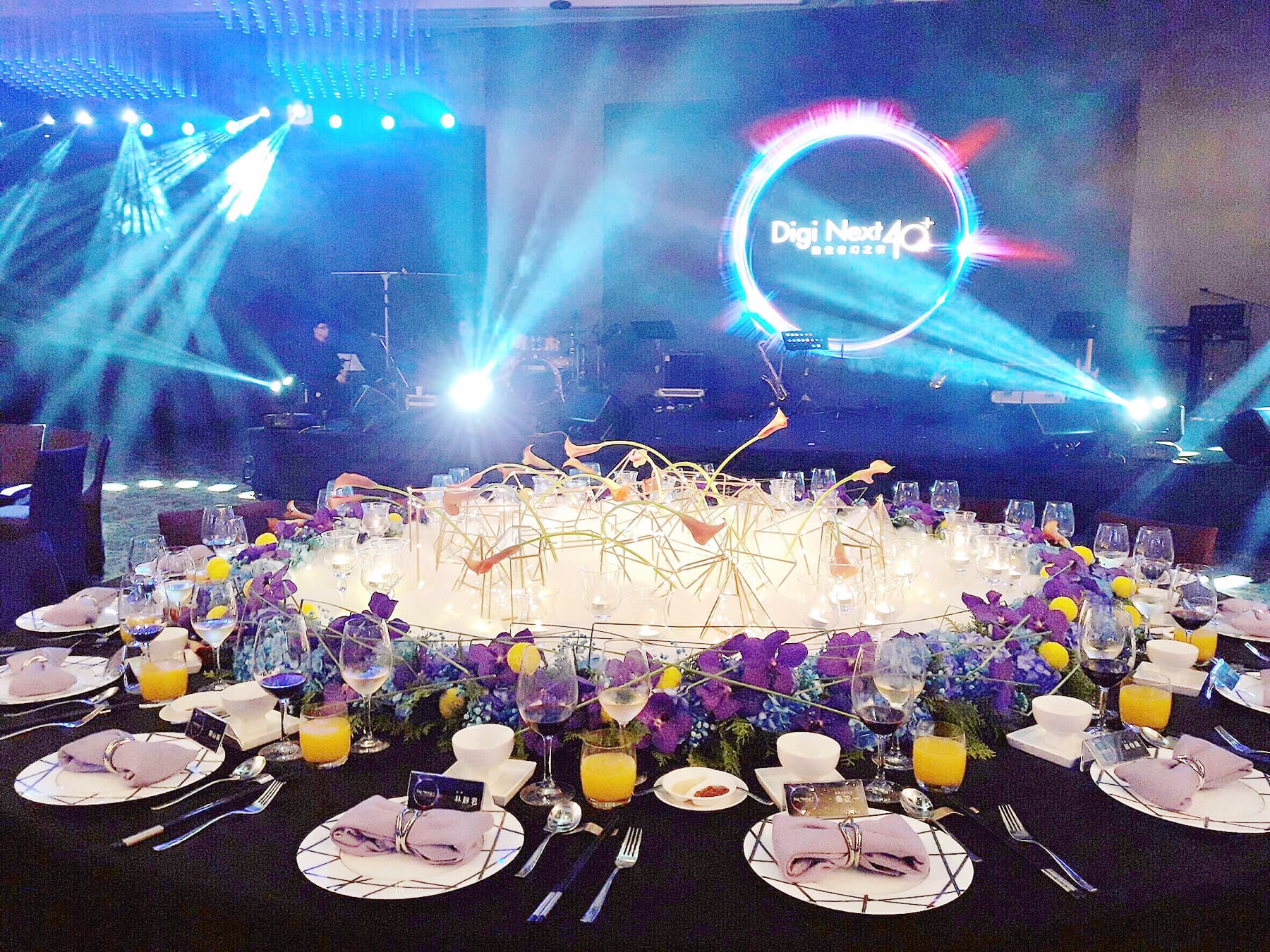 這張「婚禮」的照片是一個婚宴現場,中間擺放著一個巨大的花卉裝飾,舞臺上有一個發光的「Digi Next 4.0」標誌。