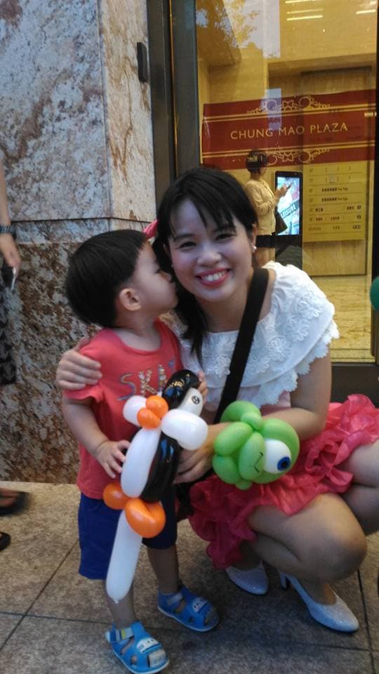 1) 照片中顯示一位年輕女子和一位小男孩,他們在一家商店前,女孩抱著男孩,並且都手持氣球