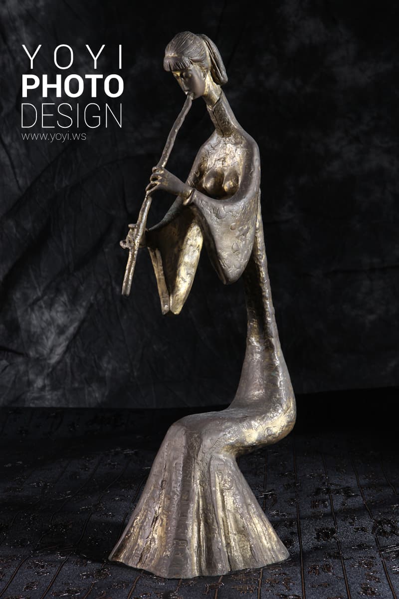 這張「雕塑」的照片是一個金色的女性雕像,她穿著長袍,正在演奏一種樂器。