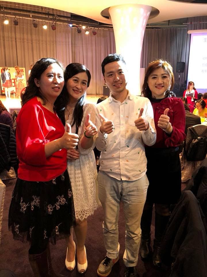 這張照片是四個朋友在一個婚禮上,他們都穿著正式的服裝,並且對著鏡頭微笑。他們看起來很開心,並且享受著這個特別的場合。