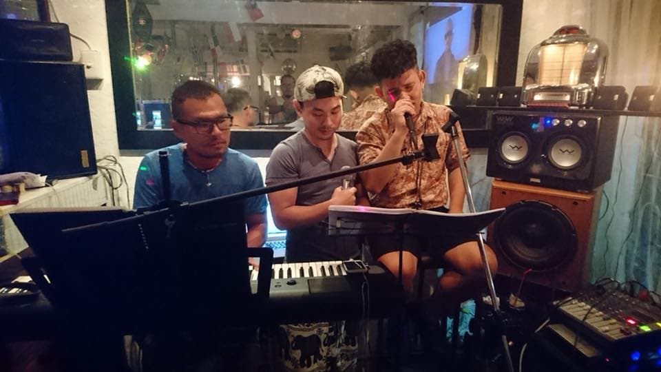 這張「音樂表演」的照片是三個男人在一個酒吧或俱樂部裡演奏音樂,其中一個人正在唱歌,另一個人正在彈鍵盤,第三個人正在伴奏。