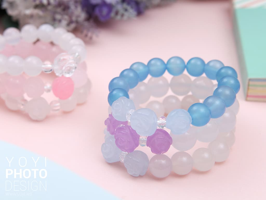 這張「手鍊」的照片是三條不同顏色的手鍊,分別是淺藍色、白色和粉色。它們都是由珠子串成,珠子上面有花朵的圖案。