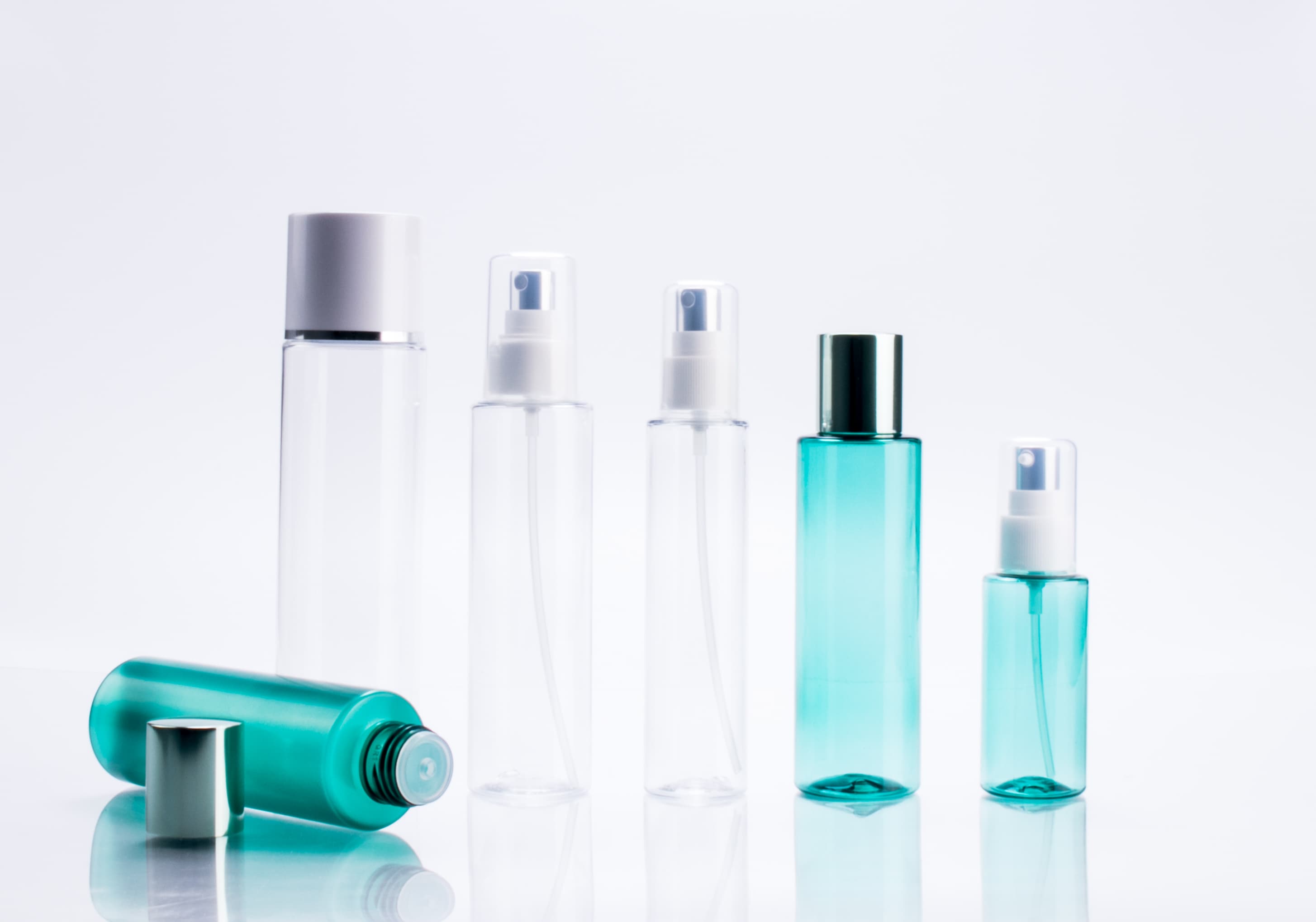 這張照片是五個不同大小的噴霧瓶,它們排成一排,最前面放了一個倒下的噴霧瓶。