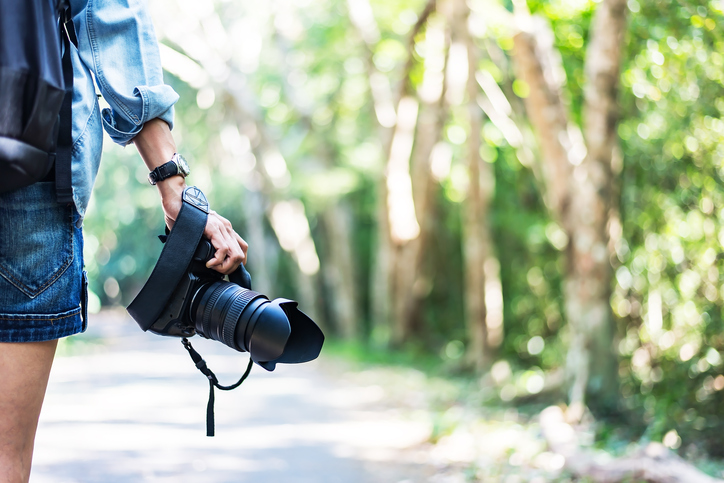 Professional woman photographer taking outdoor portraits with prime lens. Greenery tone 2017